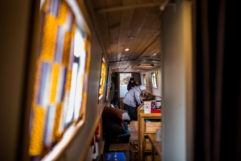 looking down the interior length of a narrow boat, two women at the far end